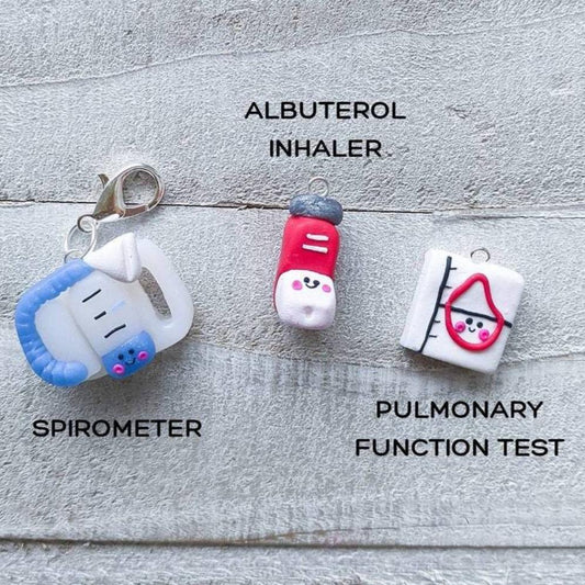 Three kawaii styled pulmonary charms – a handheld blue spirometer, red albuterol inhaler, and pulmonary function test.
